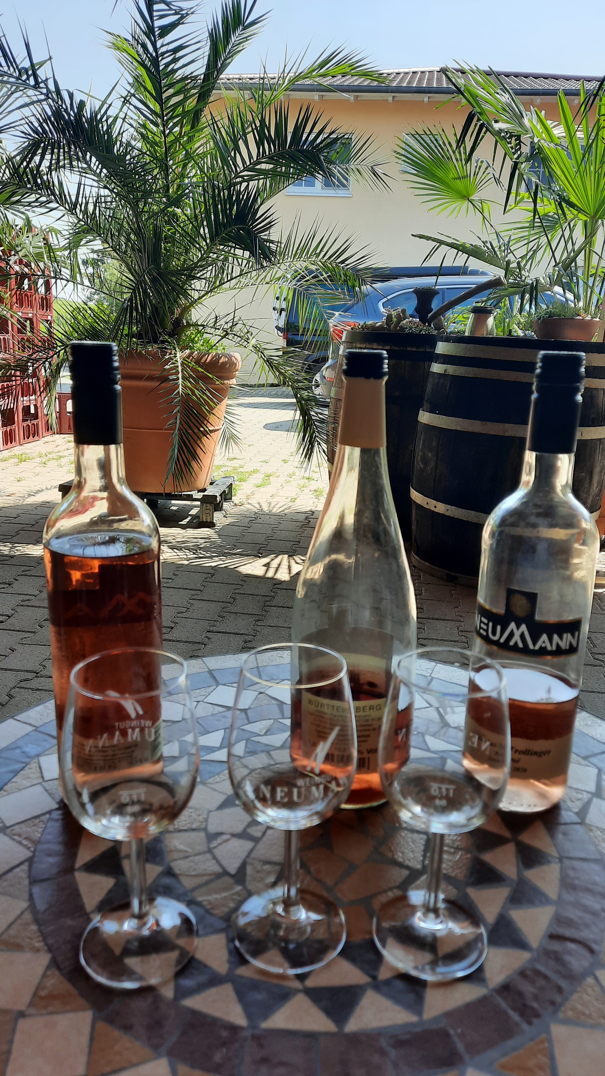 Roséflaschen und Probiergläser auf einem Mosaiktisch im Hof