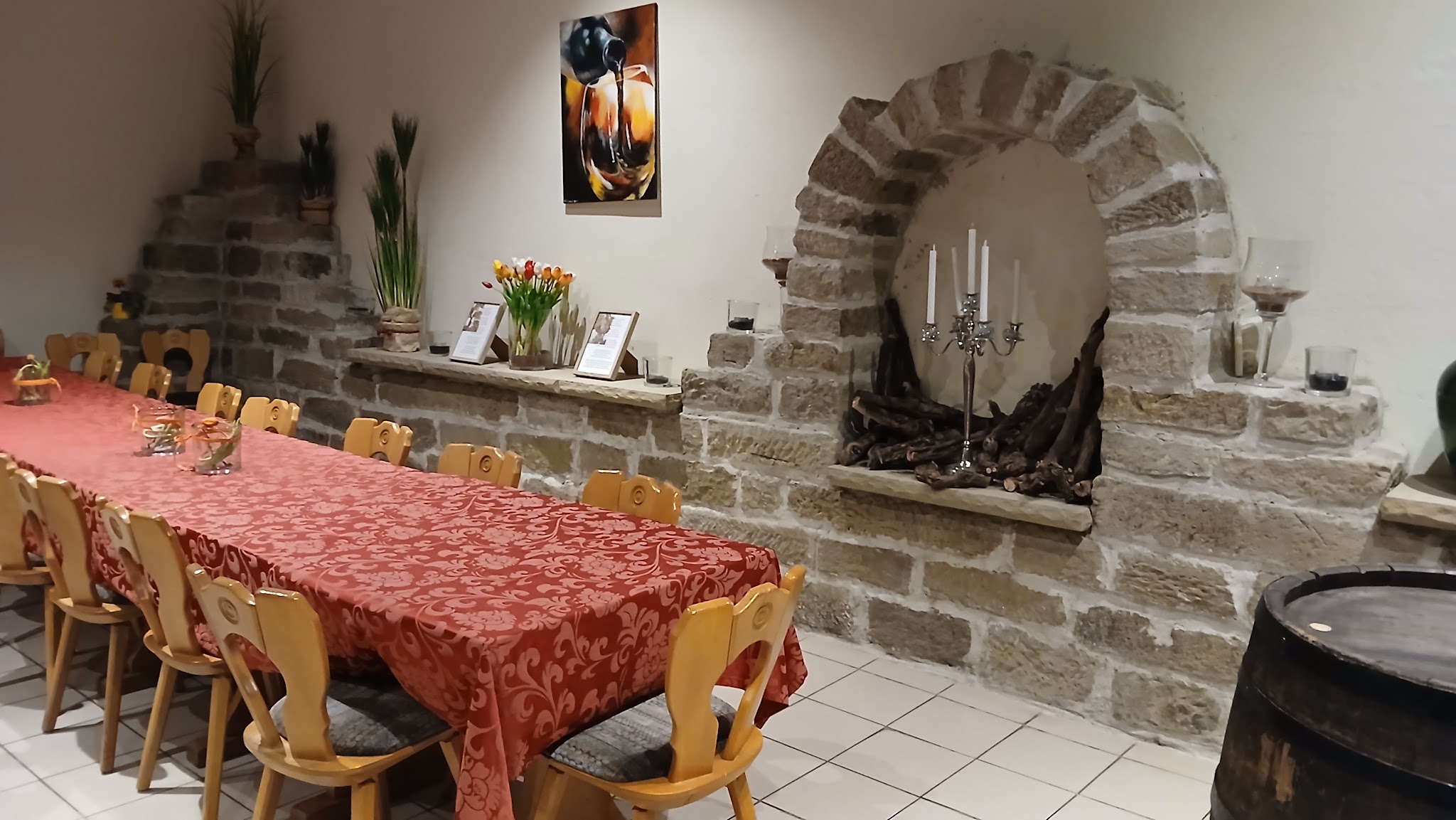 Probierraum mit langer gedeckter Tafel, Natursteinbogen und Weinfass